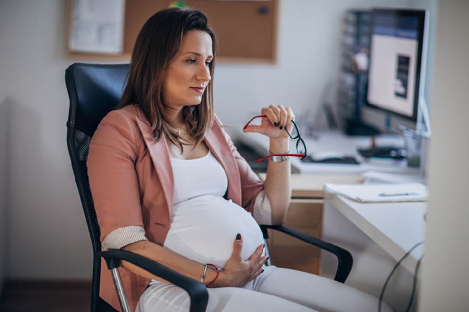 Pregnant woman holding belly at work - Pregnancy Discrimination